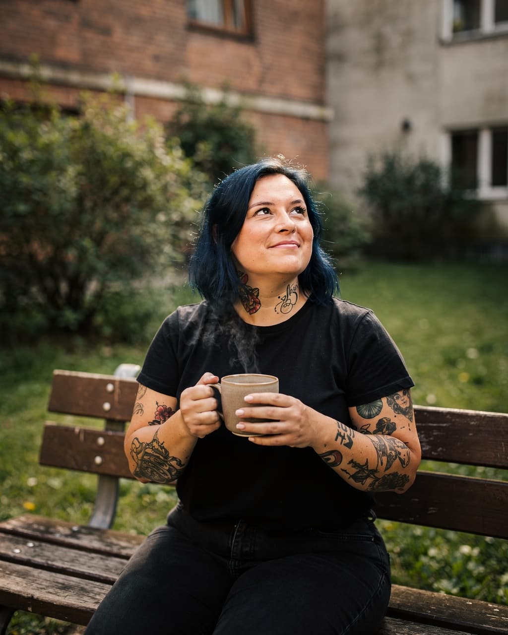 Frau macht draußen auf einer Bank eine Kaffeepause